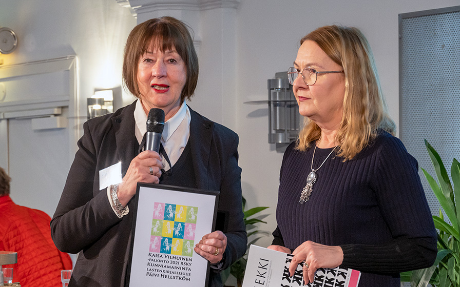 Kaisa Vilhuinen -palkinnon esittely ja Ruotsinsuomalaisen kirjoittajayhdistyksen kunniamaininnan jako lastenkirjailija Päivi Hällströmille, pj. Pirjo Lahdenperä ja Liekki-lehden päätoimittaja Tiina Pukkila Sarilidou.